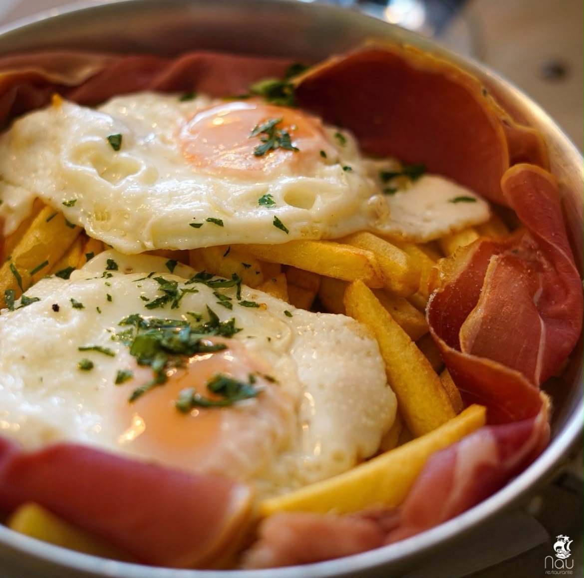 Ovos rotos com batata frita e presunto fumado servidos no Restaurante NAU